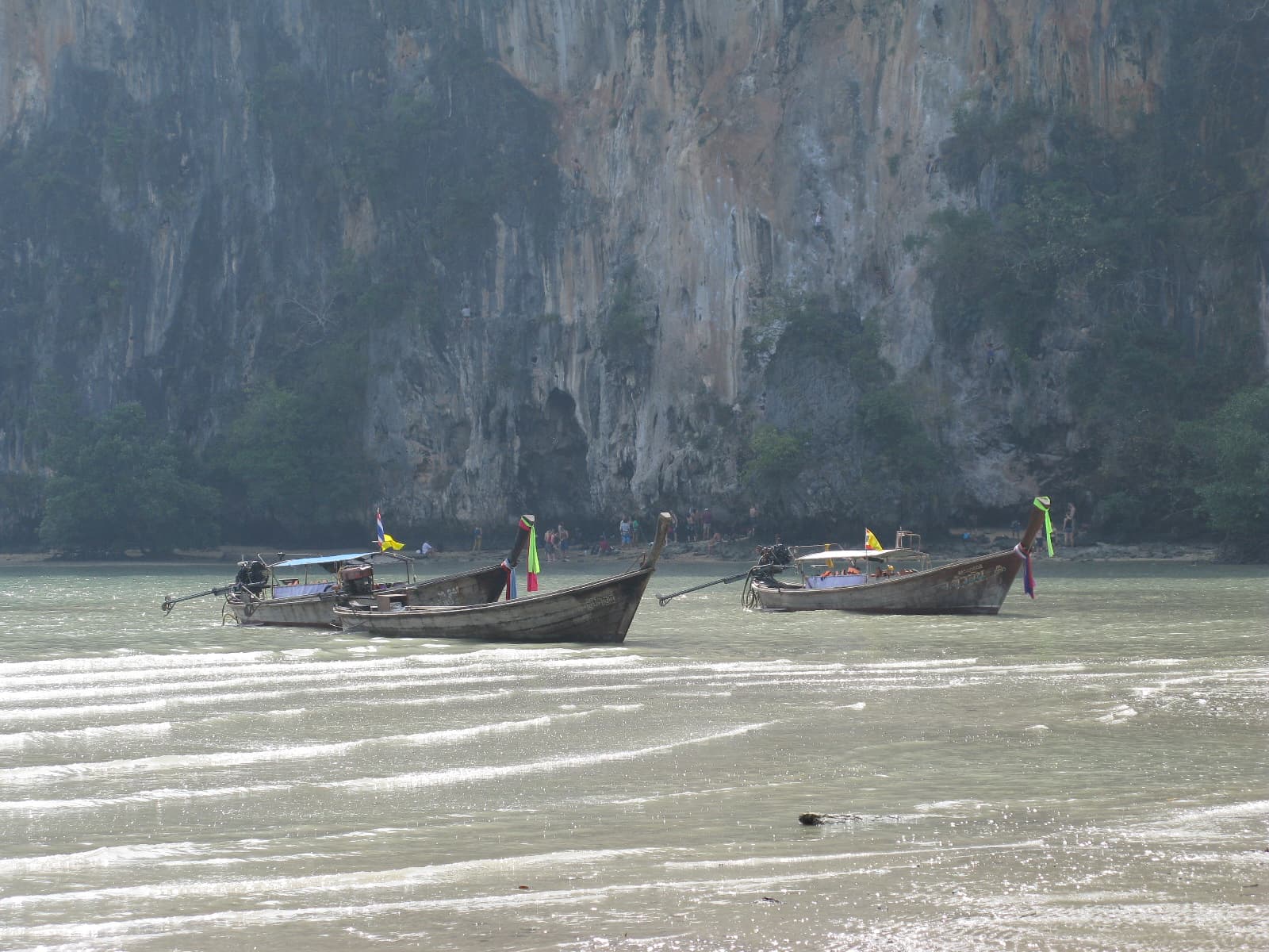 Bateaux longtail au pied des falaises calcaires de la plage de Railay, à Krabi